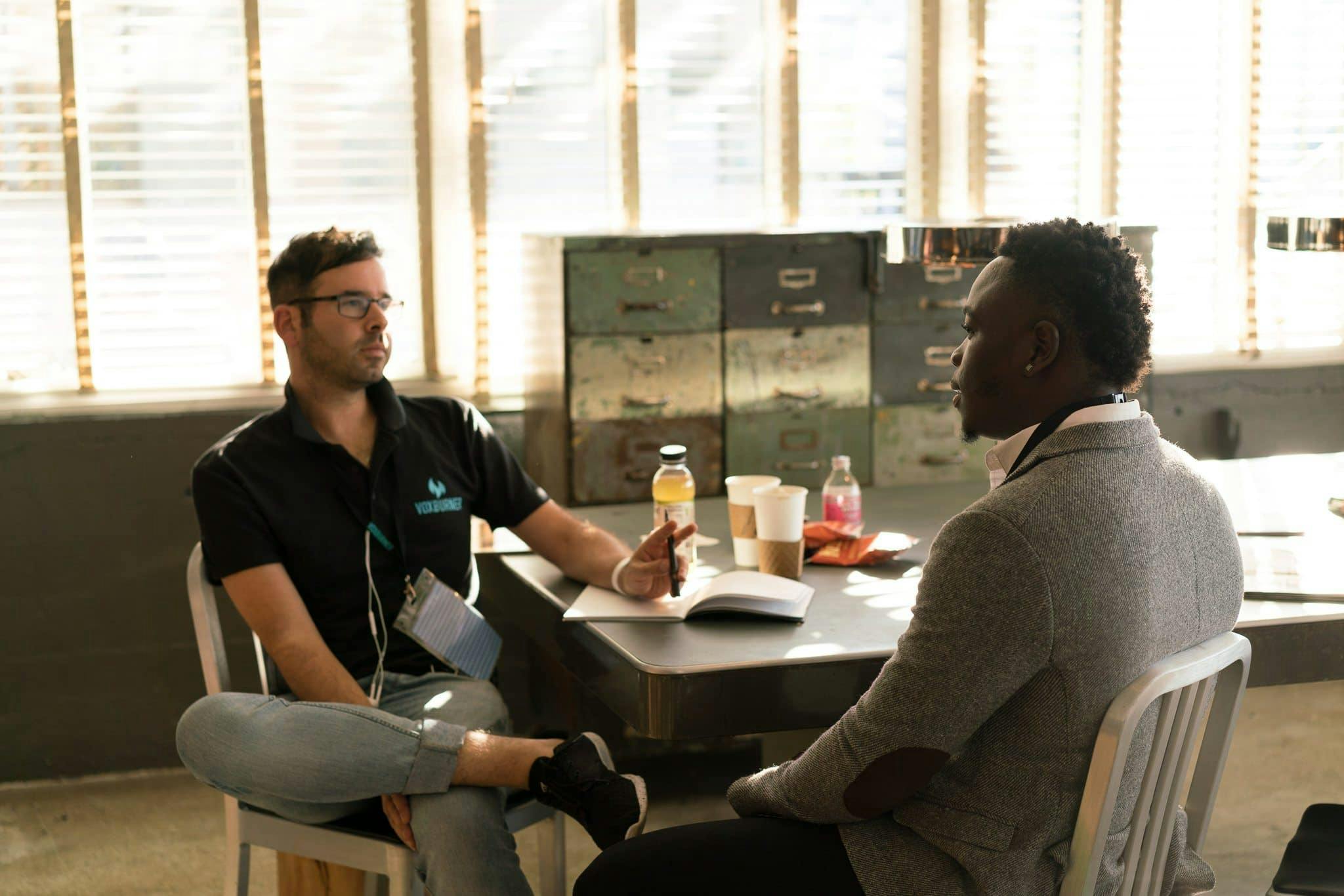 Two men sitting at a table in a business meeting in front of file cabinets